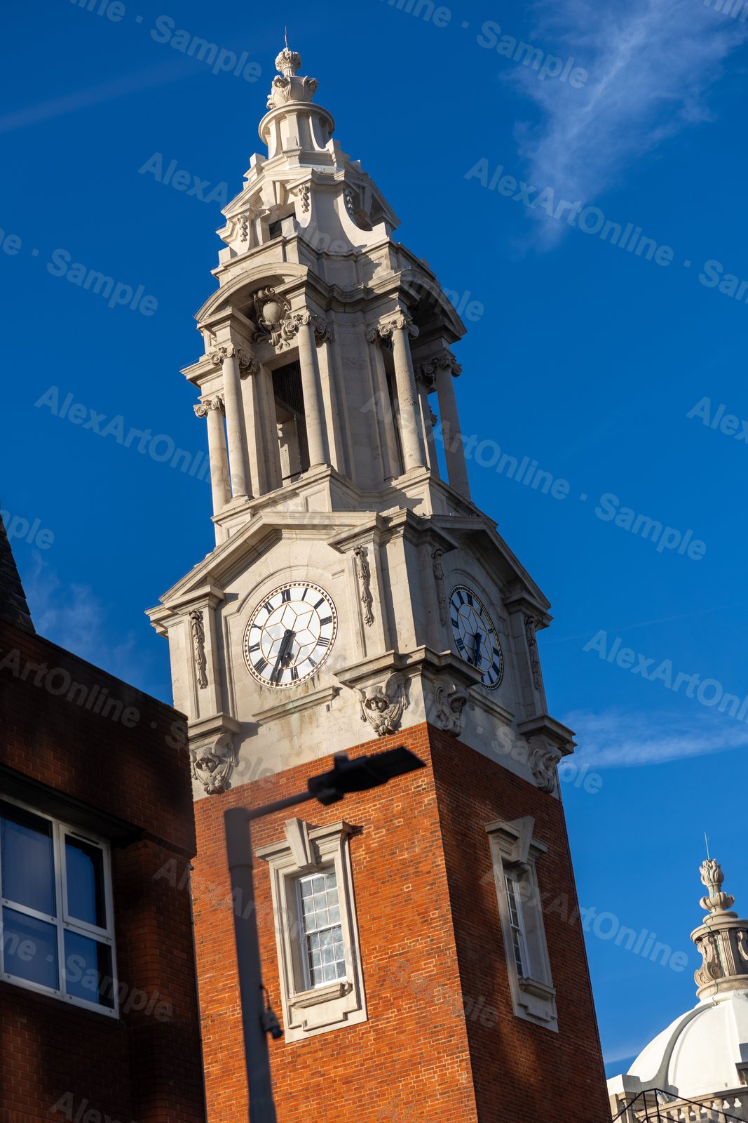 A white clock tower on red brick against a deep blue sky