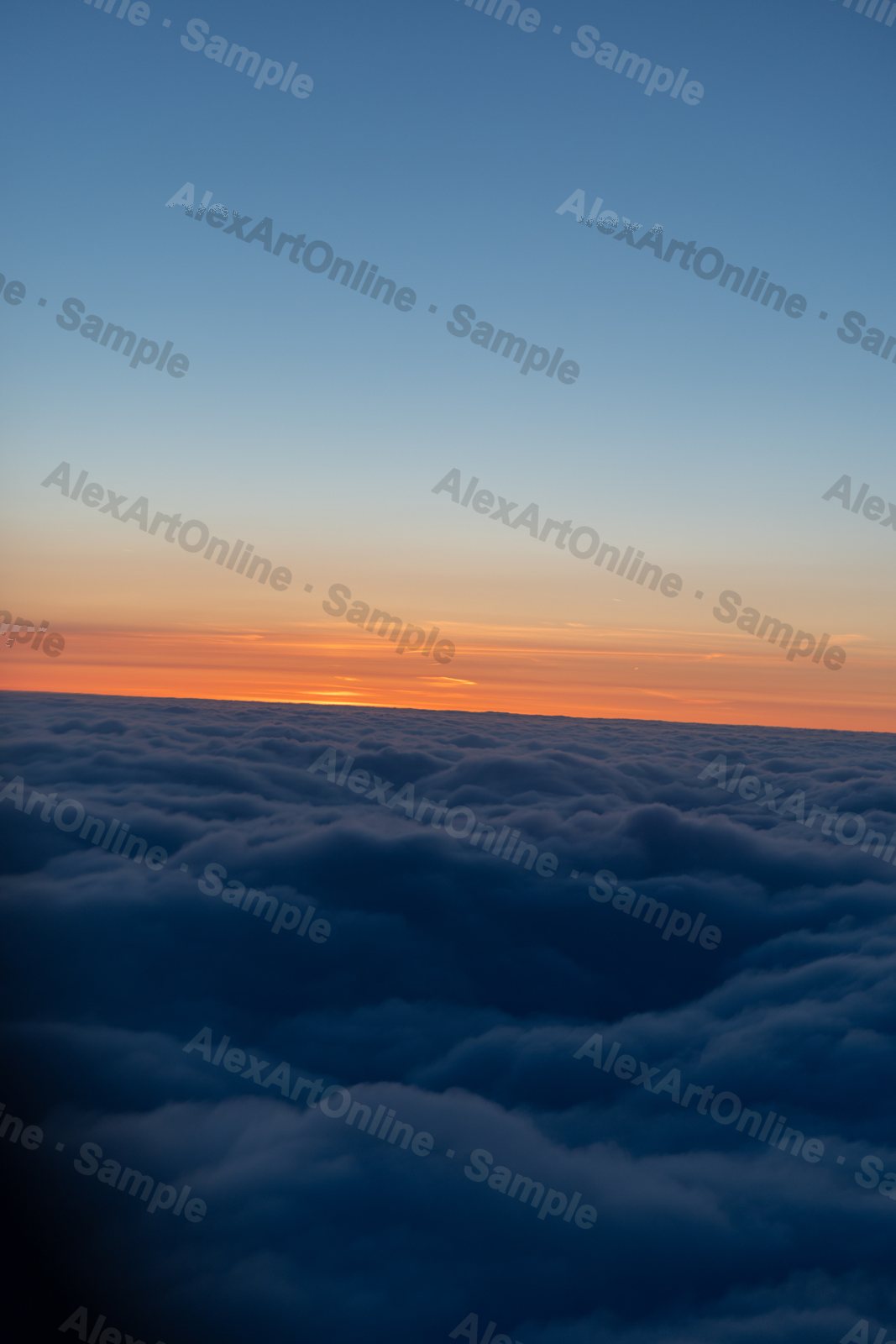 A sea of dark clouds from above with an orange sunset line
